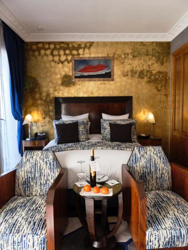 a bedroom with a bed with two chairs and a table at Hôtel particulier Le DOGE - Relais & Châteaux in Casablanca