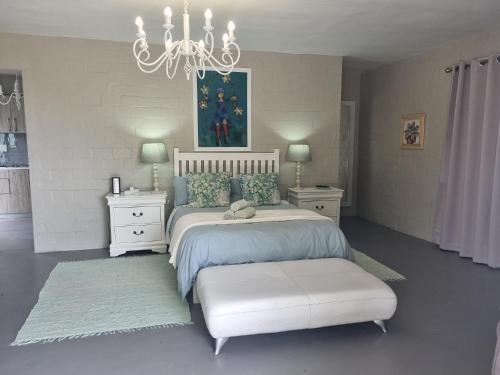 a white bedroom with a bed and a chandelier at Manatoka Unit 1 in Jacobs Bay