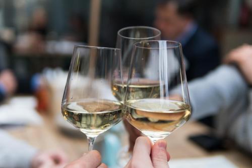 two people holding up glasses of white wine at Hôtel Expérience - Quartier Des Marinas in Magog-Orford