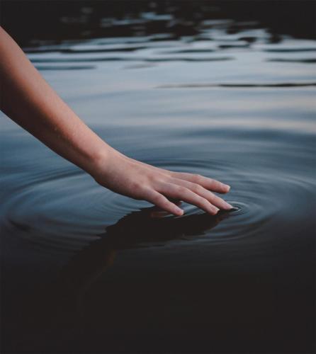 a person is reaching into the water at Hôtel Expérience - Quartier Des Marinas in Magog-Orford