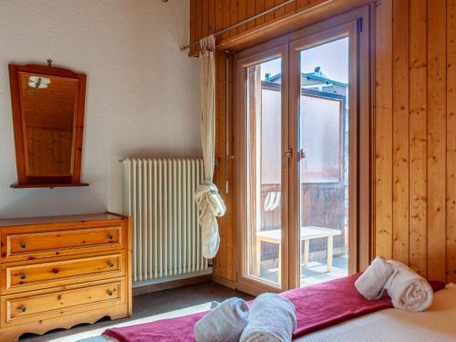 a bedroom with a bed and a dresser and a window at Apartment Derborence 25 by Interhome in Nendaz