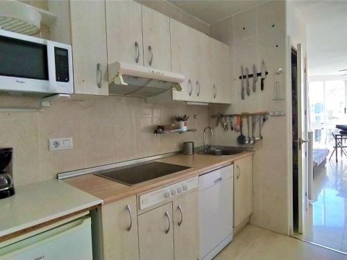 a kitchen with white cabinets and a sink and a microwave at Apartment Turia Playa by Interhome in Benidorm