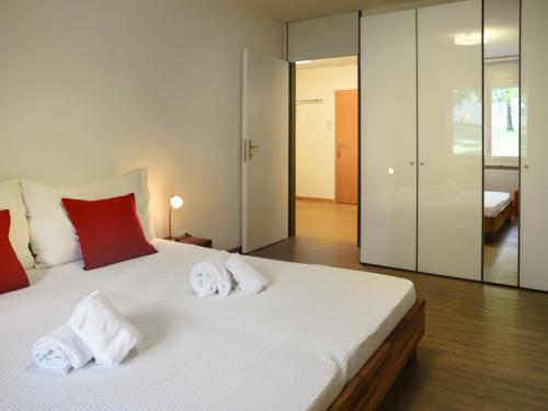 sypialnia z dużym białym łóżkiem z czerwonymi poduszkami w obiekcie Apartment Allod-Park-15 by Interhome w Davos