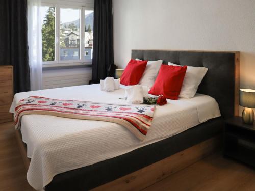 a bedroom with a large bed with red pillows at Apartment Allod-Park-46 by Interhome in Davos