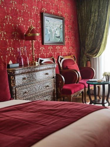 a bedroom with red walls and a dresser and chairs at Hôtel particulier Le DOGE - Relais & Châteaux in Casablanca