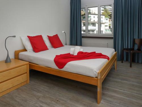 a bedroom with a bed with red pillows at Apartment Allod-Park-22 by Interhome in Davos