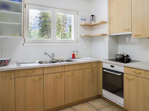 Apartment Allod Park Haus B E01 by Interhome في دافوس: مطبخ بدولاب خشبي ومغسلة