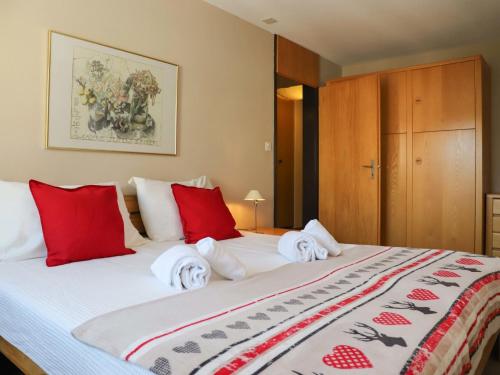 - une chambre dotée d'un grand lit avec des oreillers rouges et blancs dans l'établissement Apartment Allod-Park-48 by Interhome, à Davos