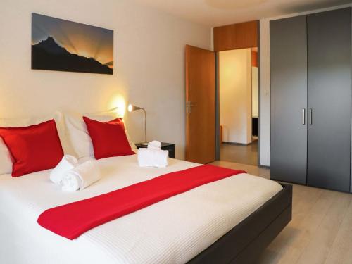 - une chambre dotée d'un grand lit avec des oreillers rouges et blancs dans l'établissement Apartment Allod-Park-49 by Interhome, à Davos