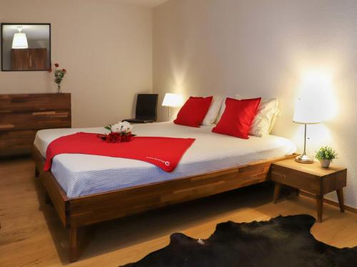 a bedroom with a large bed with red pillows at Apartment Allod Park Haus C 705 by Interhome in Davos