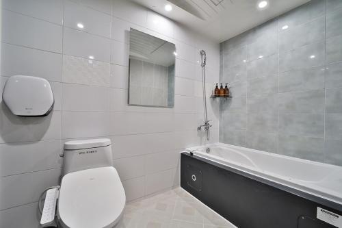 a white bathroom with a toilet and a bath tub at Evian Hotel in Gyeongsan