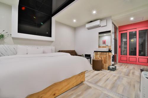 a bedroom with a white bed and a red door at Evian Hotel in Gyeongsan