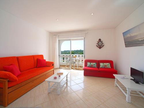 a living room with an orange couch and a red chair at Apartment Quinta Girassol-6 by Interhome in Loulé