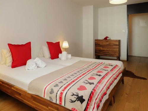 um quarto com uma cama grande e almofadas vermelhas em Apartment Allod Park Haus C 707 by Interhome em Davos
