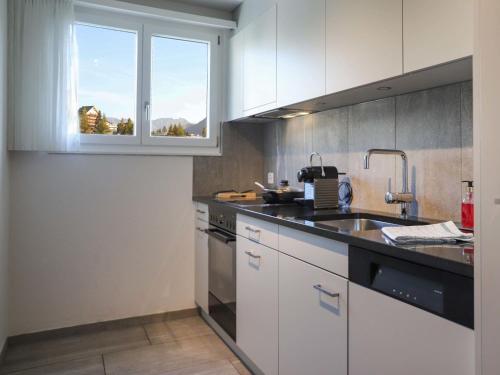 uma cozinha com armários brancos, um lavatório e uma janela em Apartment Allod Park Haus C 707 by Interhome em Davos