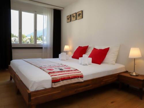 a bedroom with a large bed with red pillows at Apartment Allod Park Haus C 707 by Interhome in Davos