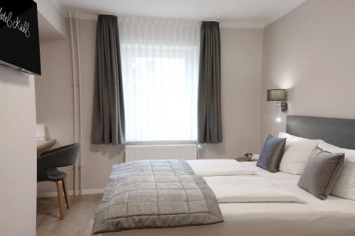 a bedroom with a bed and a desk and a window at Hotel Kühl in Neumünster