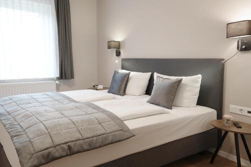 ein Schlafzimmer mit einem großen Bett mit weißer Bettwäsche und Kissen in der Unterkunft Hotel Kühl in Neumünster