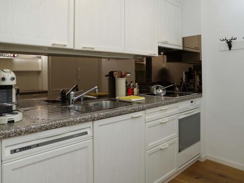 eine Küche mit weißen Schränken und einem Waschbecken in der Unterkunft Apartment Allod Park Haus C 202 by Interhome in Davos