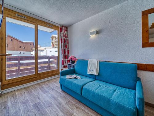 - un canapé bleu dans une chambre avec une grande fenêtre dans l'établissement Apartment Altineige 104 by Interhome, à Val Thorens