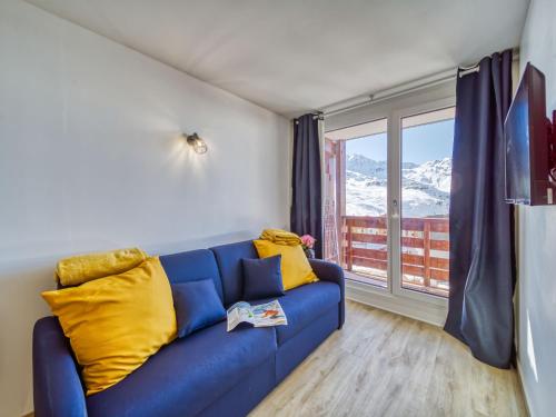 a blue couch with yellow pillows in a room with a window at Apartment Altineige-6 by Interhome in Val Thorens