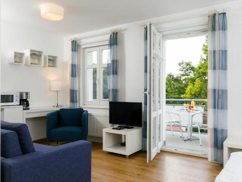 een woonkamer met een blauwe bank en een televisie bij Apartment Zinnowitzer Hof-1 by Interhome in Zinnowitz