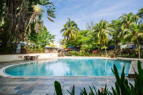 a swimming pool in a resort with palm trees at EE's Summer House - Homestay 3 min walk to beach in Batu Ferringhi
