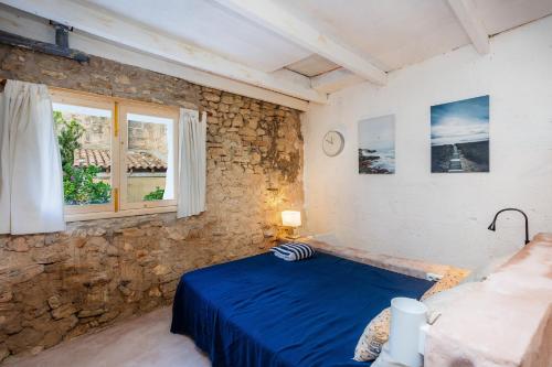 a bedroom with a blue bed and a stone wall at Can Polta in Santa Margalida