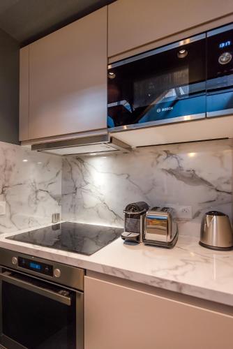 - une cuisine avec des comptoirs en marbre blanc et une cuisinière dans l'établissement Séjour au Taj proche Tour-Eiffel, à Paris