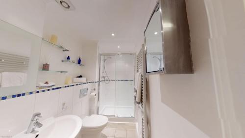 La salle de bains blanche est pourvue d'une douche et de toilettes. dans l'établissement Elizabeth Jennings Way, à Oxford