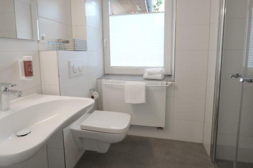 a white bathroom with a toilet and a sink at Hotel Kühl in Neumünster