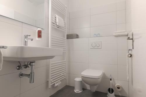 a white bathroom with a sink and a toilet at Hotel Kühl in Neumünster