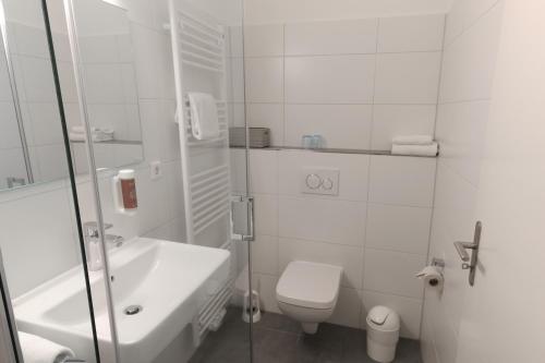 a white bathroom with a toilet and a sink at Hotel Kühl in Neumünster