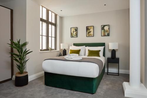 ein Schlafzimmer mit einem grünen und weißen Bett und einer Pflanze in der Unterkunft Chancery Lane by Viridian Apartments in London