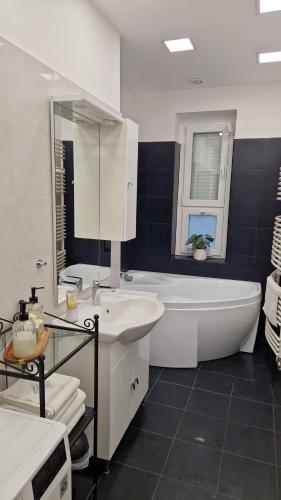 a white bathroom with a tub and a sink at Martina apartman Békéscsaba in Békéscsaba