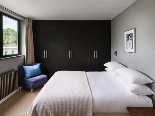 a bedroom with a large bed and a blue chair at The Kensington Penthouse Suite in London