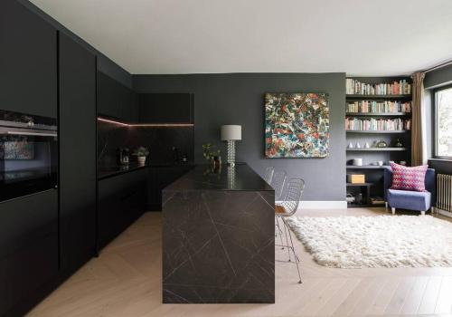 sala de estar con paredes negras, mesa y sillas en The Kensington Penthouse Suite, en Londres