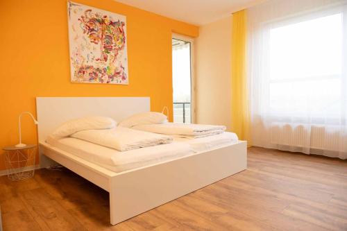Cama blanca en habitación con pared de color naranja en Art City Studio Kassel 2, en Kassel