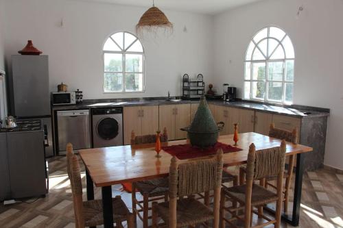 a kitchen with a wooden table with chairs and a kitchen with a tableablish at Villa Les jardins fleuris in Essaouira
