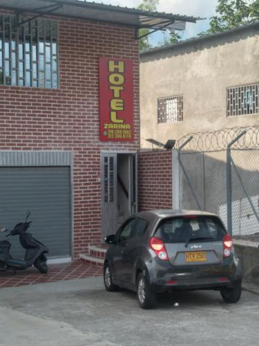 un pequeño coche aparcado frente a un edificio de ladrillo en Hotel Zarina, en Villavicencio