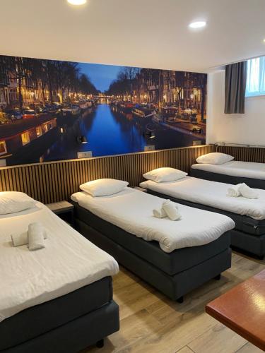 a room with three beds and a mural of a canal at Hotel Titus City Centre in Amsterdam