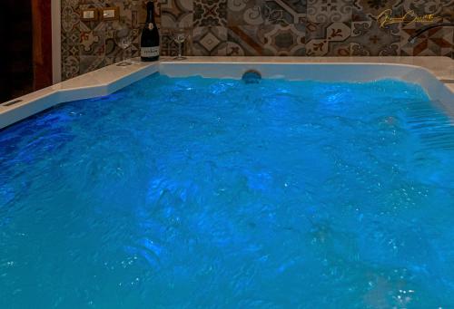 uma grande banheira cheia de água azul numa casa de banho em Victoria Luxury Suite em Lizzanello