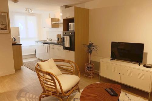 a living room with a television and a chair at Jaurès - Centre ville - T1 bis au calme in Brest