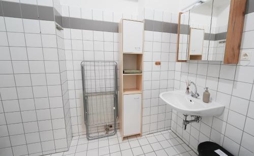 un bagno piastrellato bianco con lavandino e specchio di CozyNite Premium Apartment Hernals 1 a Vienna