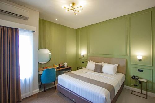 una camera con letto, scrivania e finestra di Hotel FortunaGrande Malioboro Yogyakarta a Yogyakarta
