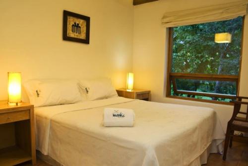 a bedroom with a white bed with two lamps and a window at Manke Apart & Suites in San Martín de los Andes