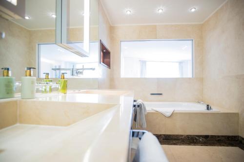 a bathroom with a tub and a sink and a window at Iris Porsche Hotel & Restaurant in Mondsee