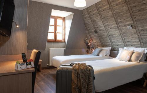 a hotel room with two beds and a suitcase at Logis Hôtel-restaurant Les Coudercous in Saint-Chély-dʼAubrac