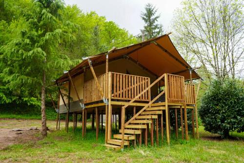 a large wooden house with stairs in a forest at Camping Pittoresque in Saint-Parthem