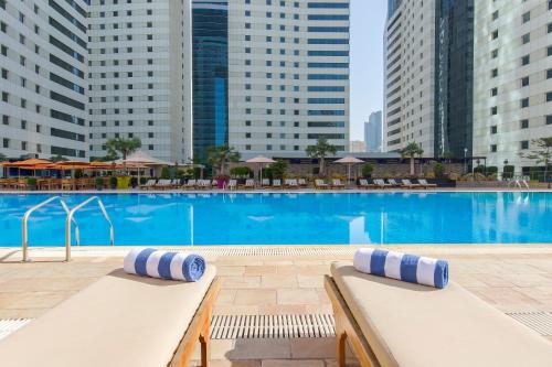 a large swimming pool in a city with tall buildings at Ezdan Hotel Doha in Doha